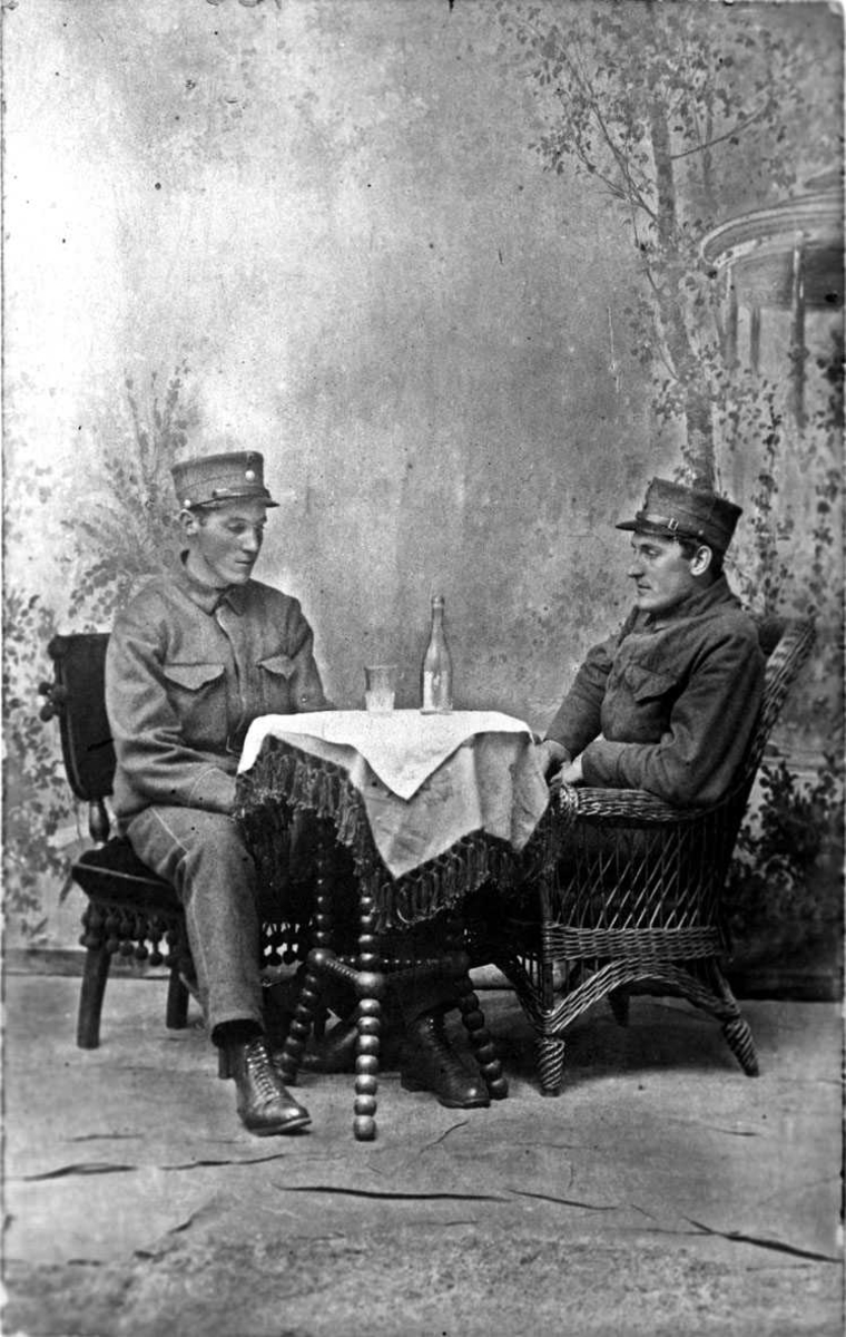 To soldater sittende ved et bord. Atelierbilde.