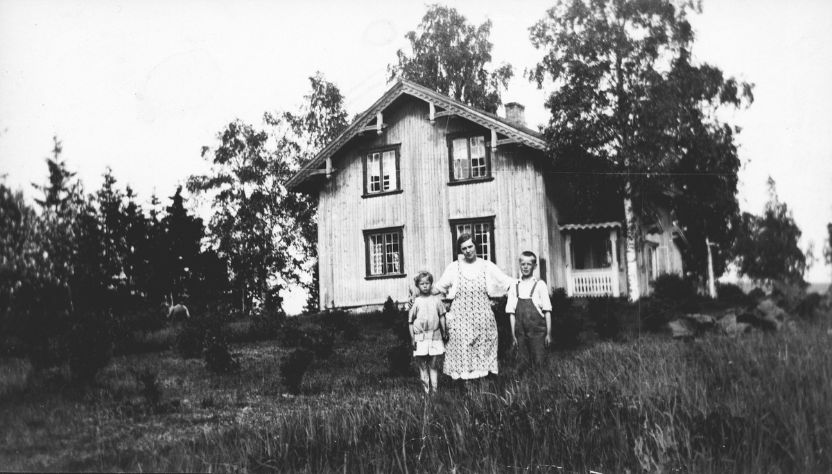 Mor og barn i hagen foran hus i sveitserstil