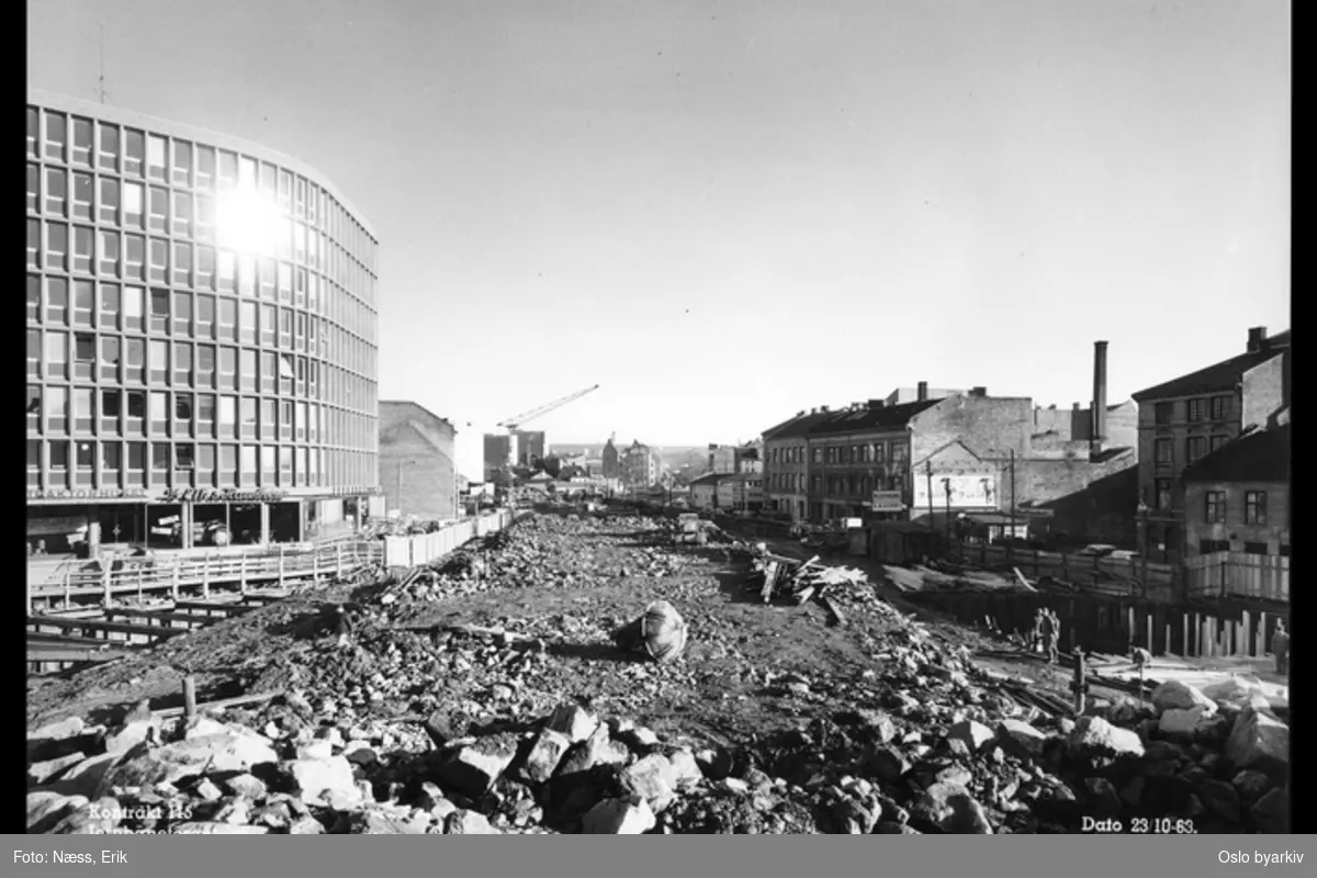 Byggingen av Jernbanetorget stasjon, Traktorhuset i Nygata 12 til venstre, Vaterland saneres. Bilde datert 23. oktober 1963.