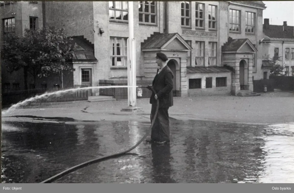 Vaktmesteren spyler skolegården. Albumtittel: "Sofienberg skole femti år - første september 1933."