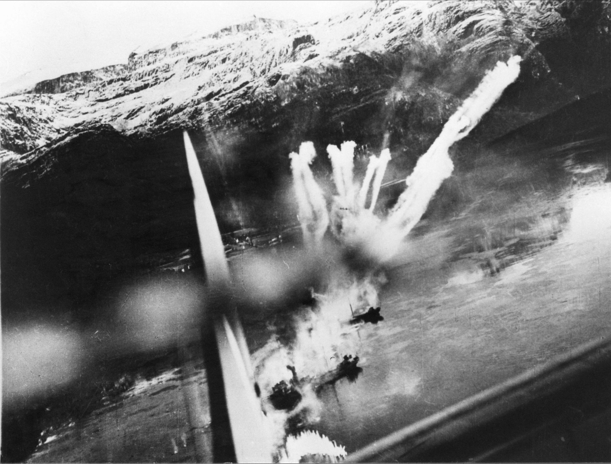 Angrep på skip i Nordgulen, 5. desember 1944. Røyksporene fra raketter og brannene ombord i fartøyene kan sees bak halen på Mosquito-flyet.