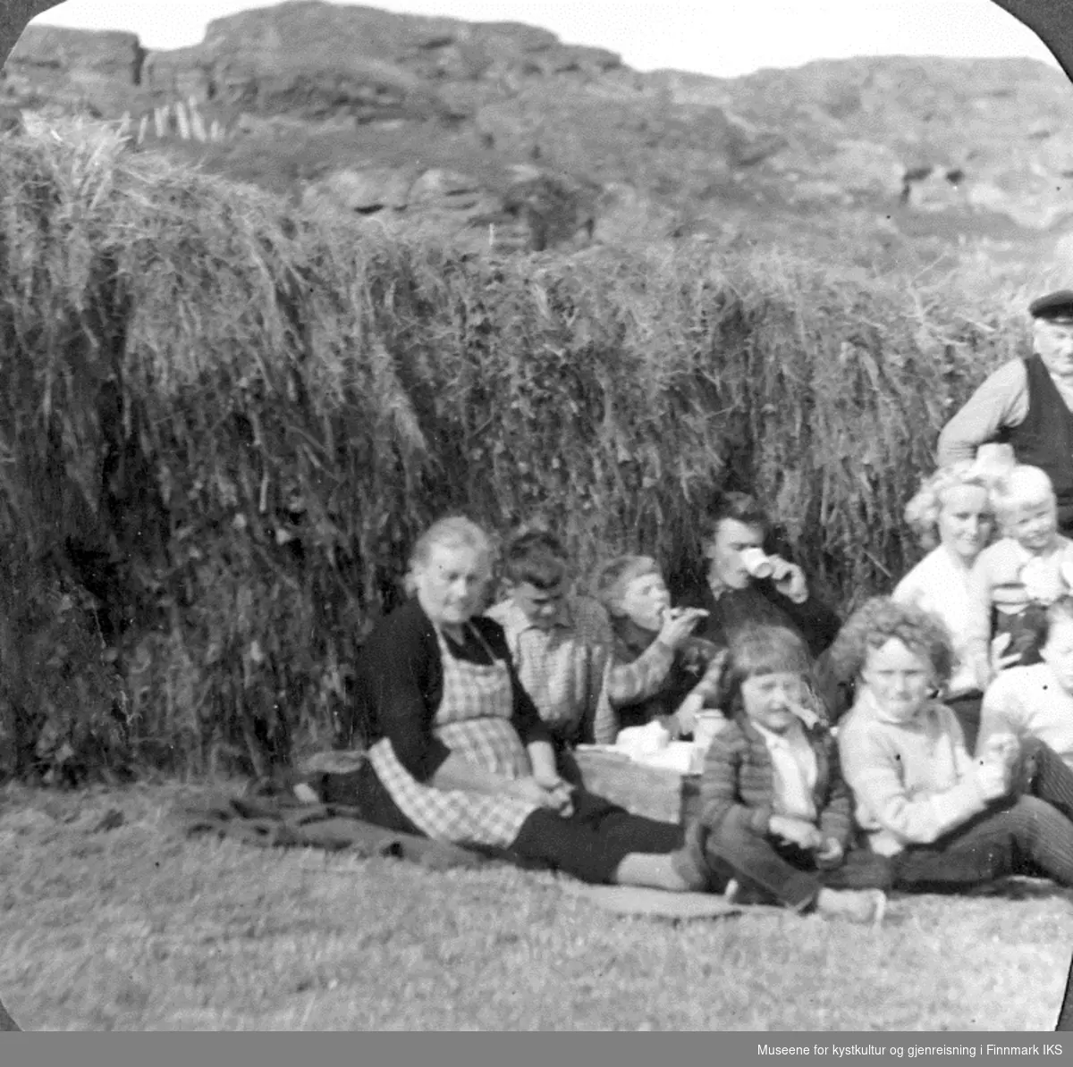 Landkomberget på Ingøy omkring 1960. Familien Petter Pettersen tar en pause i høyhesjingen og slåingen.Hans sønn Henrik Pettersen og noen av hans barn hjelper til.