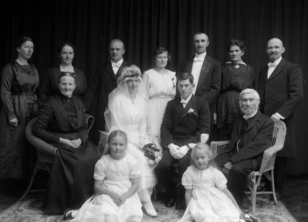 Dystvold J. , brudepar m/familie gr: 13, ukjente. Bryllupet til  Antonie Hansen og Jens Dystvold. Sittende på venstre og høyre er foreldrene til Antonie og , over skulderen til Jens står Einar Hansen.