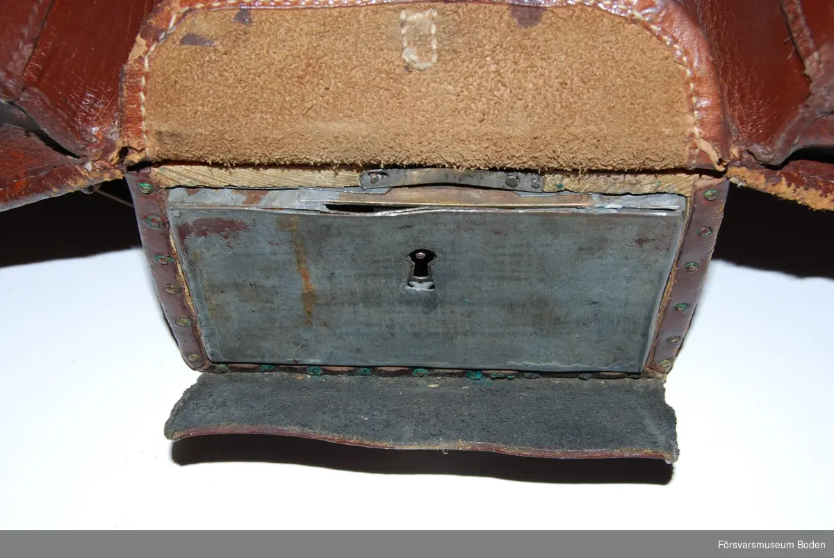 Utvikbar väska av brunt läder med låsbar låda av bleckplåt i botten, nyckeln saknas. Innehåller blanketter, kuvert, linjal m.m. (moderna utgåvor). Se AM.078470 för modellexemplar.