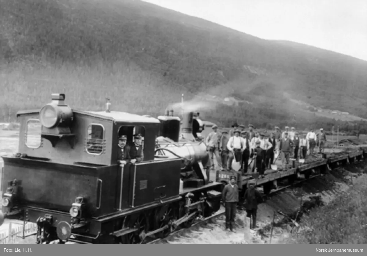 Damplokomotiv type 25a nr. 26x foran grustog, med oppstilte grusningsmannskap