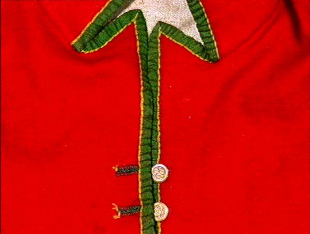 Katalogkort: Brudgomsvest med krager. Rødt klede, kantet med grønne bånd. Sju metallknapper 
