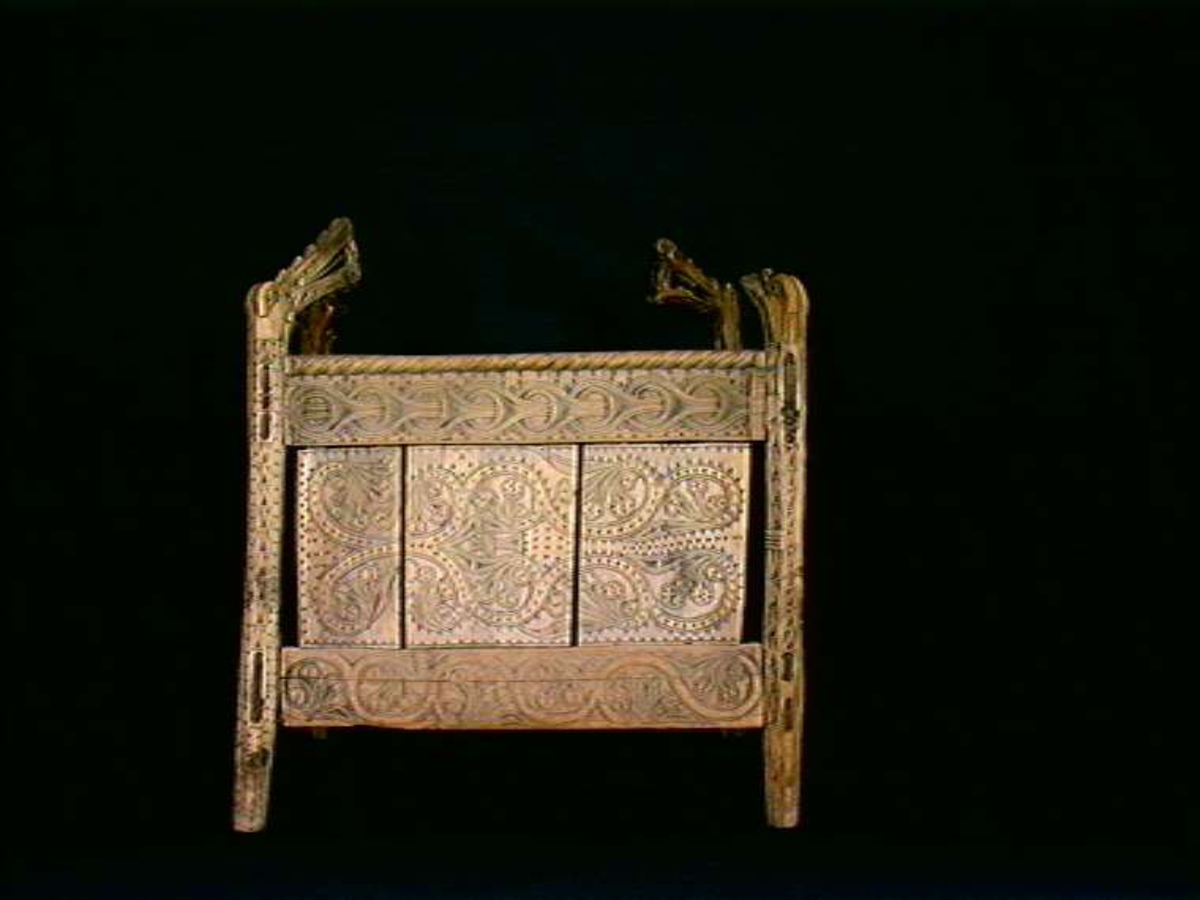 Fire søyler med skåret dyrehode-ornamentikk, sammenføyet med tverrbord og fyllinger. Bunn er åpen foruten to tverrstaver. Hele utsiden er rikt dekorert med utskåret dyr og ranker.