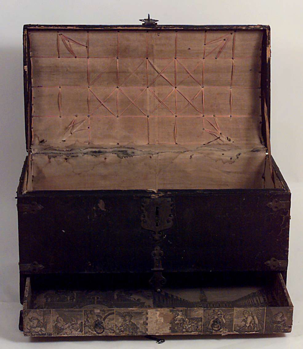 Kiste med buet lokk. Trukket med preget lær utvendig. Innvendig foret med tekstik. I fronten en låsbar skuff foret med kobberstikk med datering "Decem 1651"