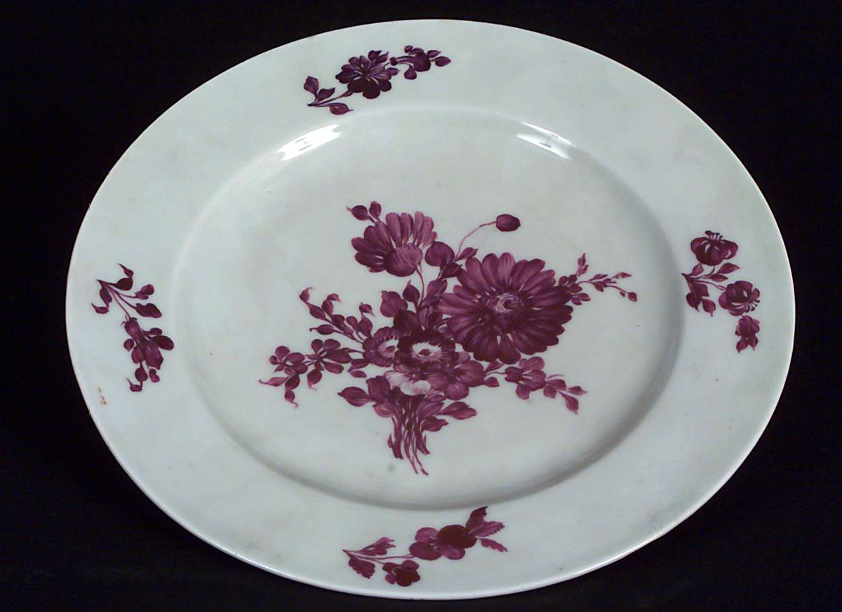 Tallerken i porselen, hvit med rosa blomstermønster i bunn og på kantene.