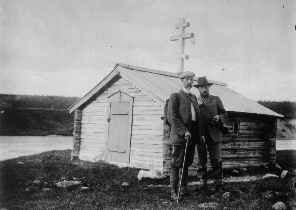 Russisk-ortodoks kapell, med russisk kors, Neiden, Sør-Varanger, Finnmark, 1904-1905. Lege Andreas B. Wessel med kikkert t. h. sammen  med mann med stokk.