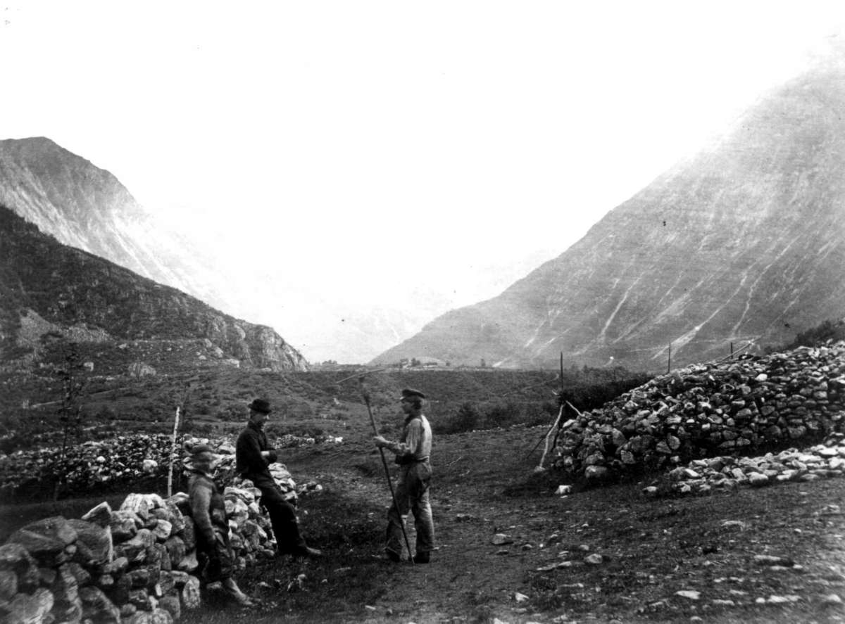 (13,5x18cm) 
Norangsdalen, Steingjerder og mennesker som møtes i landskapet.
Fjell i bakgrunnen.