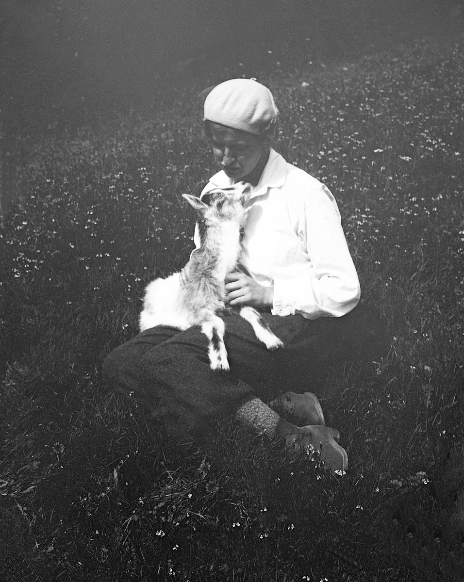 Dordi Arentz sitter med en geitekilling i fanget, Hol, Hallingdal. Fotografert 1932.
