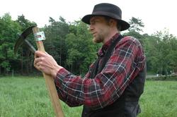 Fra slåttonna i juni 2005.Vert i drakt, sliper ljåen.