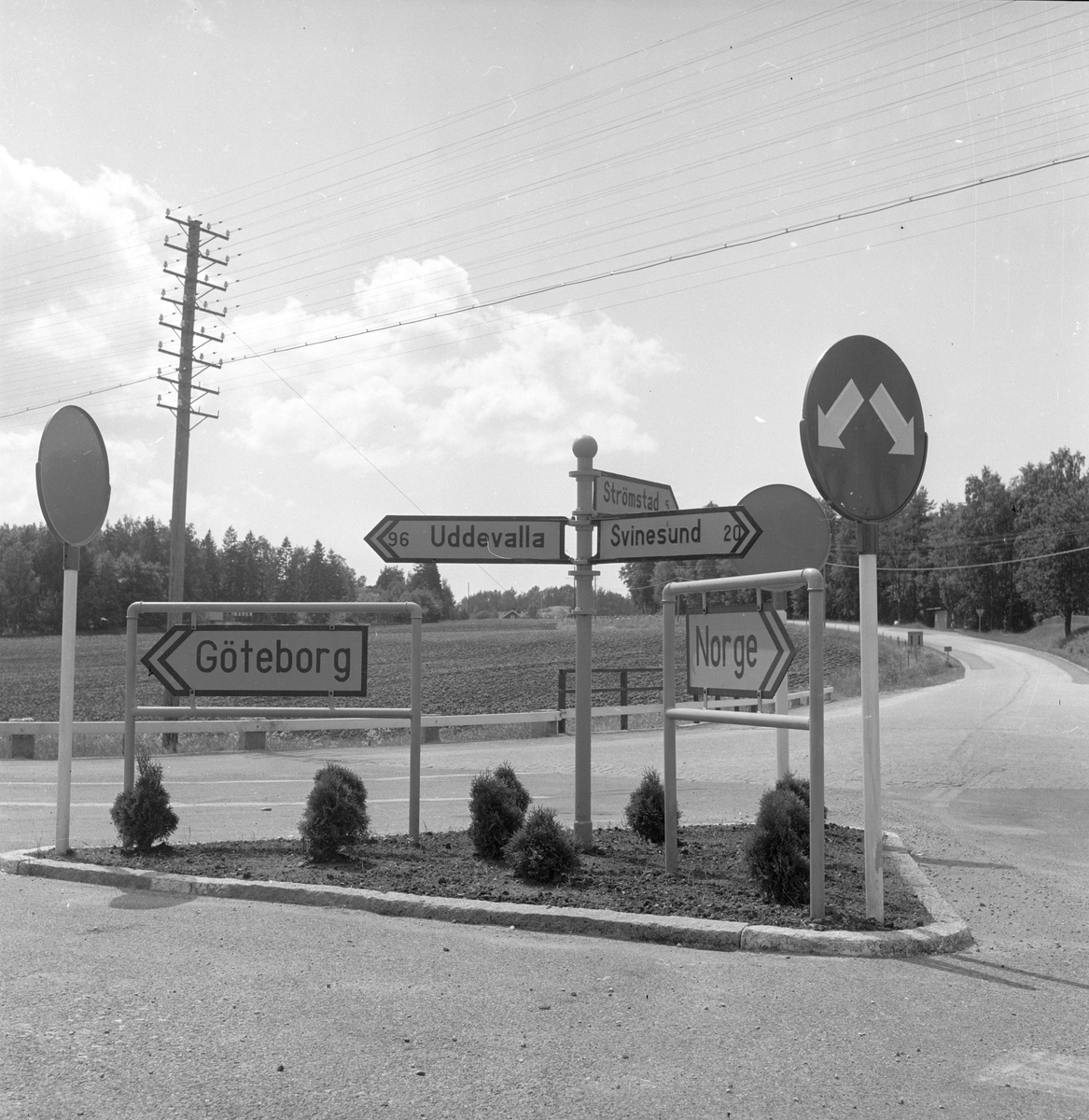 Langs Riksvei 1 i Sverige, står det en trafikkøy med skilt som henviser til Norge, Strømstad, Göteborg etc. Fotografert 7. juli 1958.