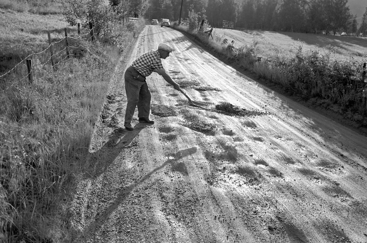 En mann med spade reparerer en dårlig vei i Halligdal. Fotografert juli 1967.