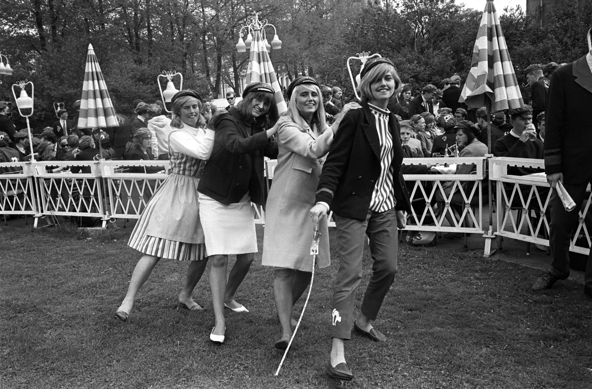 Russen danser jenka og viser russemoter på gressplenen utenfor uterestauranten Pernille i Oslo i mai 1965. Antatt russeprinsesse danser først i rekka.