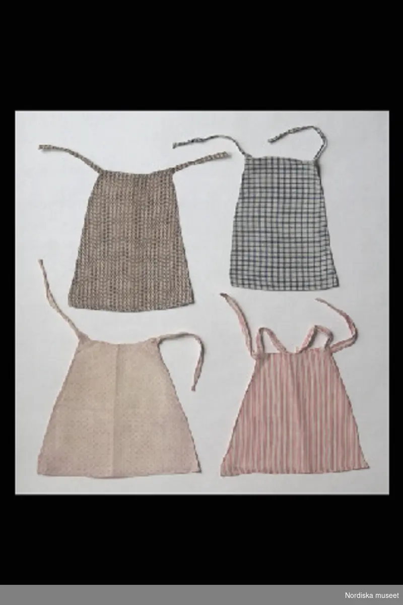 Inventering Sesam 1996-1999:
H 31 (cm) 
Docka, damdocka, 2 st, "Fru och Mamsell Medberg", huvud med sköld av papier maché, krederat och målat, och kropp i stoppat tyg, b) med skinnarmar. Målade ansiktsdrag, röd sluten mun, svarta ögon och enkelt svartmålat hår med tinningslockar. Strumpor av vit bomullstrikå och svarta, platta sidenskor fastsydda på kroppen. a) med halsband av glaspärlor.
Lintyg, 7 st (c-i), av vitt linnetyg, med kort ärm, några spetsprydda, (g) och (i) med broderat "j". Kalsonger, 7 st (j-p), av vitt bomulls/linnetyg, (j) och (o) med brodyr nedtill. Underkjolar, 6 st (q-v), av vitt linnetyg. Nattröja, (x), av vitt linnetyg, lång puffärm, krage med spetskant och knytband i halsen. Kjolar, 3 st, z) av grönt siden med färgade bårder nedtill, saknar linning, y) av svart siden, saknar linning, å) av grönt linnetyg, med 2 st rosa bårder, paljetter och fåll med insydd snodd. Klänningar, 2 st (ä,ö) av randigt sidentyg i rosa och vitt, med kort ärmpuff, tvärgarneringar och insydda snoddar. Klänningar, 10 st, med lång ärm, a:1) svart siden, 
tvärgarneringar nedtill, b:1) gräddvitt siden, kort ärm, c:1-d:1) 2 st, vitt bomullstyg med ljusbruna prickar, e:1) bomullstyg, tryckt, vitt med blå blad- och blommönster, kjolen med volanger nedtill, f:1) bomullstyg, randat i vitt, ljusblått och mörkblått, g:1) bomullstyg, tryckt, vitt med rött vegetativt mönster, gigotärm, h:1) bomullstyg, randat i rött och vitt, 2 st snoddar insydda nedtill, i:1) bomullstyg, vit- och rödrutigt, vita ärmar, "vingar" på axlarna, skärp av vitt sidenband och j:1) linnetyg, vit, kortärmad. Förkläden, 4 st, av bomullstyg, tryckt mönster, knytband, k:1) vit- och brunmönstrat, l:1) blå- och vitrutigt, m:1) vit- och rosamönstrat och n:1) röd- och vitrandigt. Slängkappor, 2 st, o:1), med kapuschong, violett ylletyg, fodrat med rosa siden och rosa kantgarnering och p:1) cape/slängkappa, av grönt ylle, fodrad med gult siden (på väg att fransa sig), med "vingar" och krage, dekorerad med grönt snörmakeri. Hattar, 4 st, q:1) bredbrättad, klädd med svart felb, dekorerad med svarta fjädrar, sidenfoder, vit tyll inuti, r:1) bahytt, klädd med rosa siden, prydd med tygblommor och silkessnoddar, knytband, vit tyll inuti, s:1) bahytt, klädd med ljusviolett siden, prydd med tygblommor och silkessnoddar, knytband, vit tyll inuti och t:1) bahytt, klädd med gräddvit siden, prydd med tygblommor, silkessnoddar och sidenrosett, knytband, vit tyll inuti.
Underkjol (v) saknas, januari 1997.                  
Anna Womack 1997