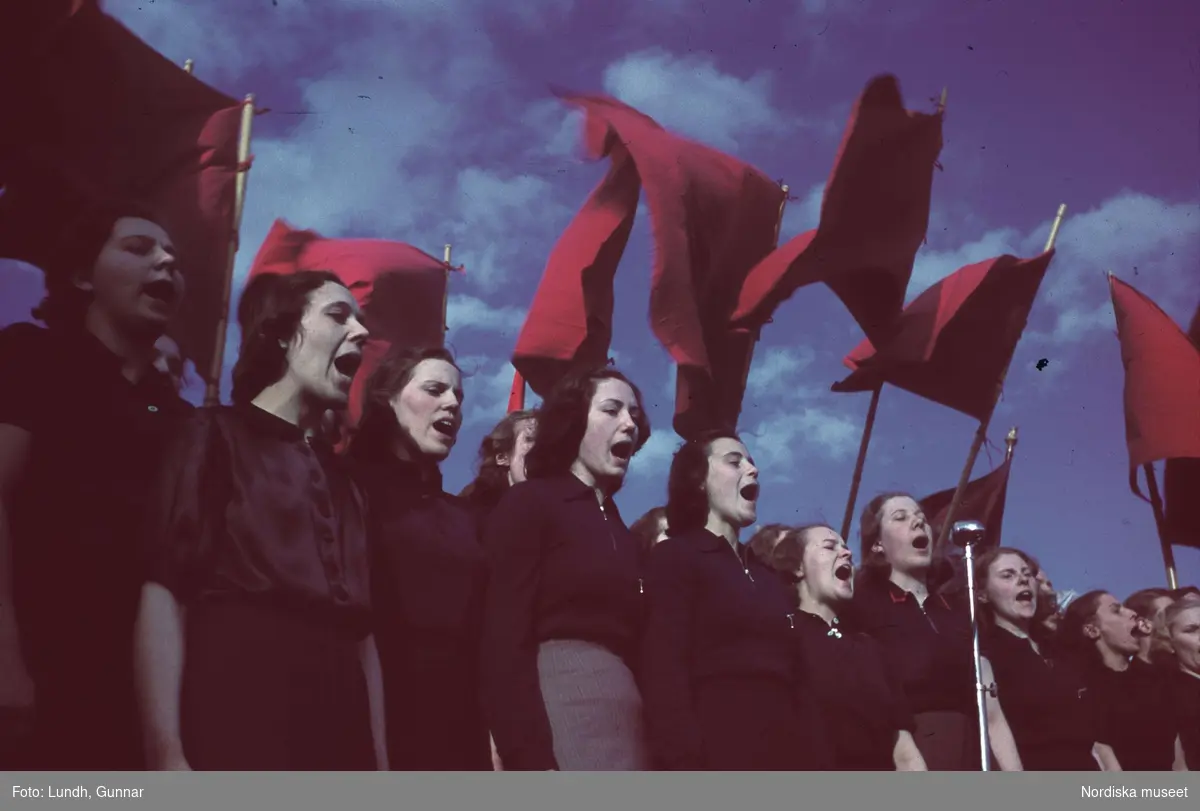 Demonstration. Kvinnor sjunger vid röda fanor.