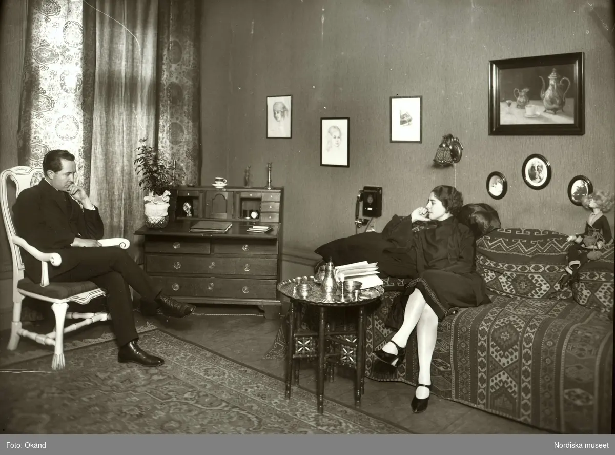 Vardagsrum eller herrum. Interiör. Ett okänt par i tidstypiskt 20-talsrum med bl.a. ottoman klädd med kelim, sidenkuddar och orientaliskt rökbord.