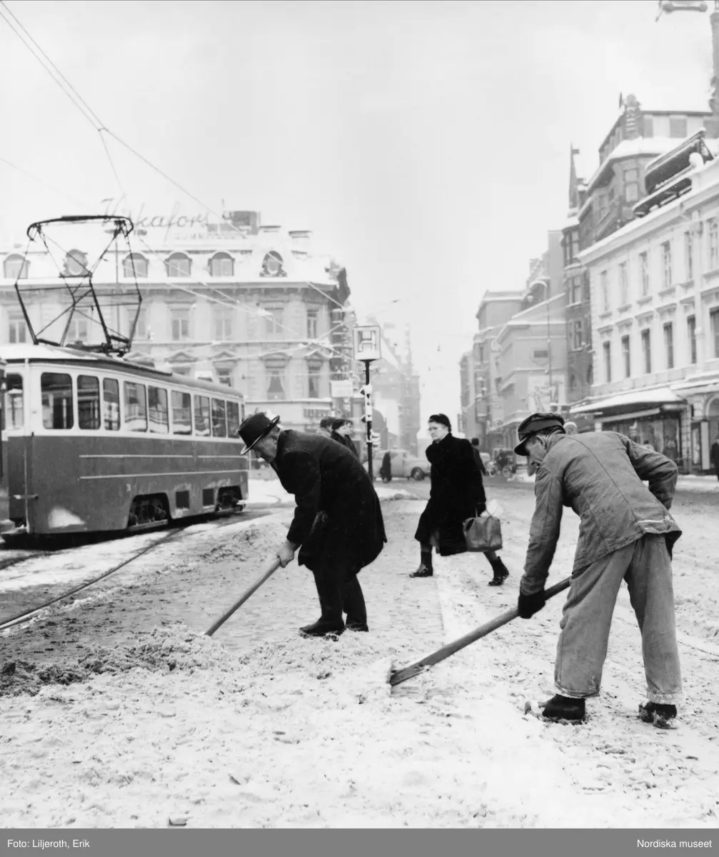 Två män skottar snö i Malmö centrum