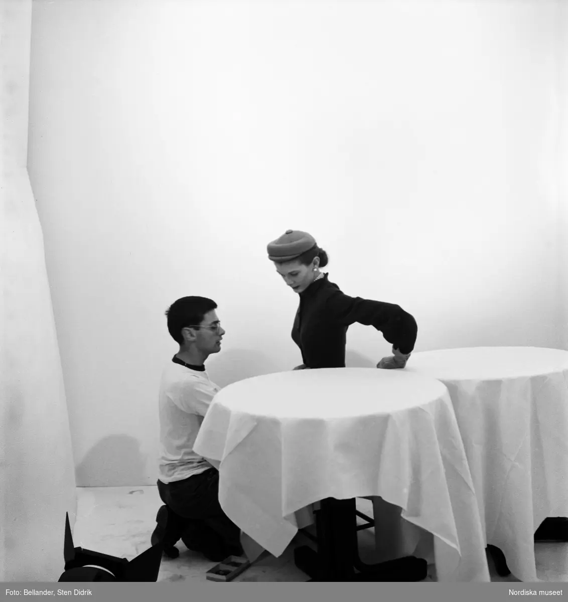 Den amerikanske fotografen Richard Avedon rättar till klädseln på en kvinnlig modell. Fotostudio.