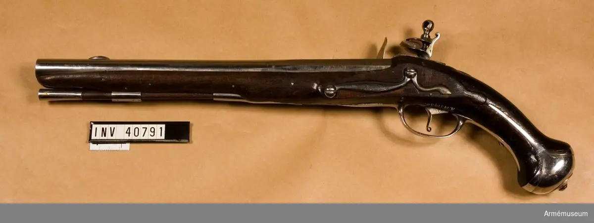 Grupp E III.
Pistol från 1700-talets början. Loppets relativa längd: 19,1 kal. pistoler bildande namnchiffer på vänstra kortväggen i II:2.