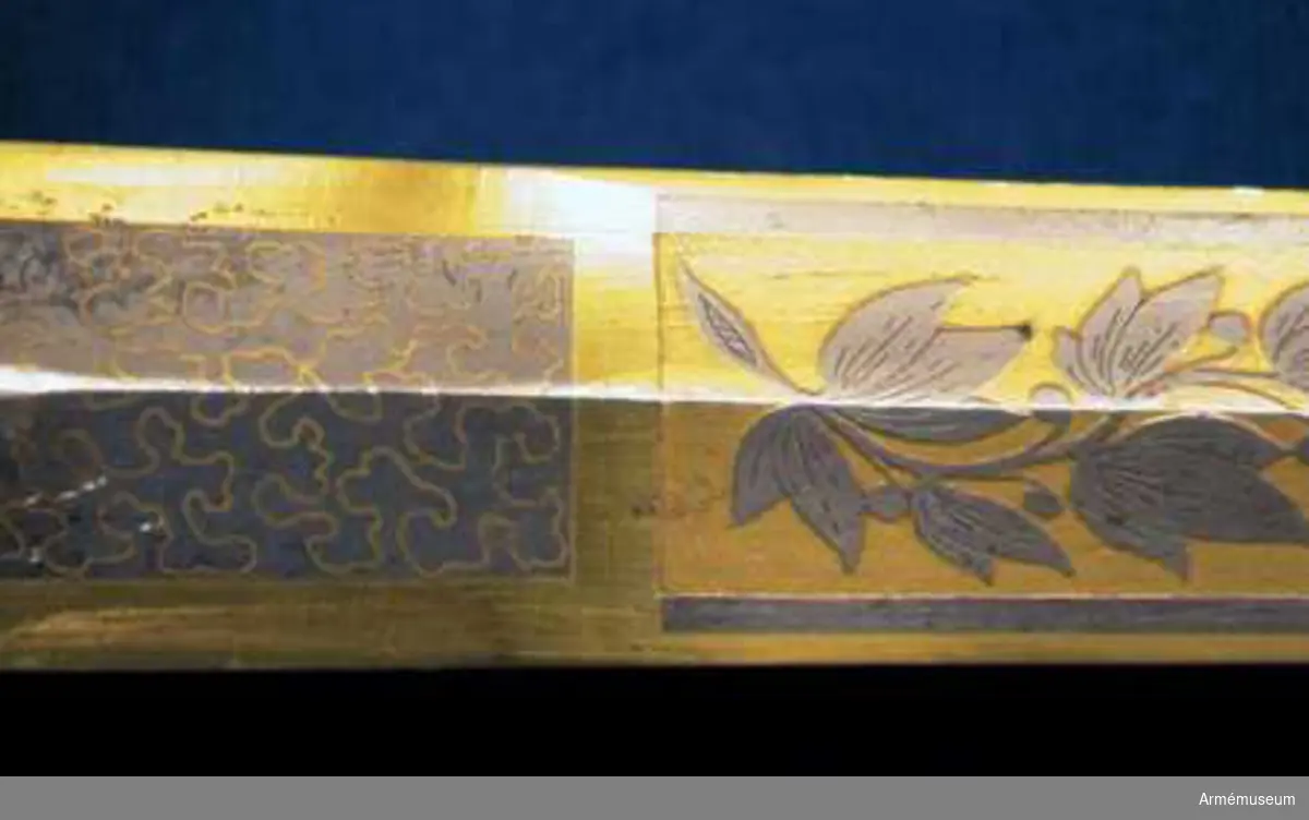 Grupp D II.
Klingan är tveeggad med ryggar. På vardera sidan är den på en längd av omkring 32 cm prydd med blanka, etsade ornament på förgylld botten, däribland på yttersidan Karl XIV Johans namnchiffer och en ranka med lagerlöv, på insidan med tre kronor under kunglig krona samt en ranka med eklöv och ollon. Fästet är av förgylld mässing och av karolinsk kavallerityp. Knappen har formen av ett tillplattat klot samt har fram och bak en rygg markerad av en längs kanterna upphöjd rand. Nitknappen är rätt hög, svagt fasonerad och med ganska stor fot. Nedtill  fortsätts knappen av en på mitten instrypt hals. Runt halsens nedre del går en rand. Gränsen mellan hals och knapp samt mellan knapp och nitknapp är tydligt markerad. Kaveln omges upp- och nedtill av ett ringliknande, omkring 5 mm brett beslag av förgyllt mässingsbleck. Längs varje kant pryds dessa beslag av en ingraverad rand. I övrigt är kaveln lindad  med en tunn, av två parter hopsnodd försilvrad koppartråd. Parerstången vidgas rätt kraftigt mot de i trepass avslutade ändarna samt har ovalt tvärsnitt. Längs dessa övre och undre, främre och bakre kanter går en upphöjd rand. Parerplåten är hjärtformig. Dess förhöjda kanter är på mitten vidgade och har på samma ställe en kantig utbuktning på den mot plåten motsatta sidan. Handbygeln vidgas rätt kraftigt på mitten och har ovalt tvärsnitt. Dess övre ände är medelst en skruv fäst vid knappen. Längs över- och undersidan på de förhöjda kanterna samt längs handbygelns främre och bakre kant löper en upphöjd, smal rand. På översidan av parerplåtens yttre hälft är de ciselerade bokstäverna F J O (Frans Josef Oskar) fastnitade och på samma sida av den inre hälften är en kronprinskrona i liknande arbete fäst.