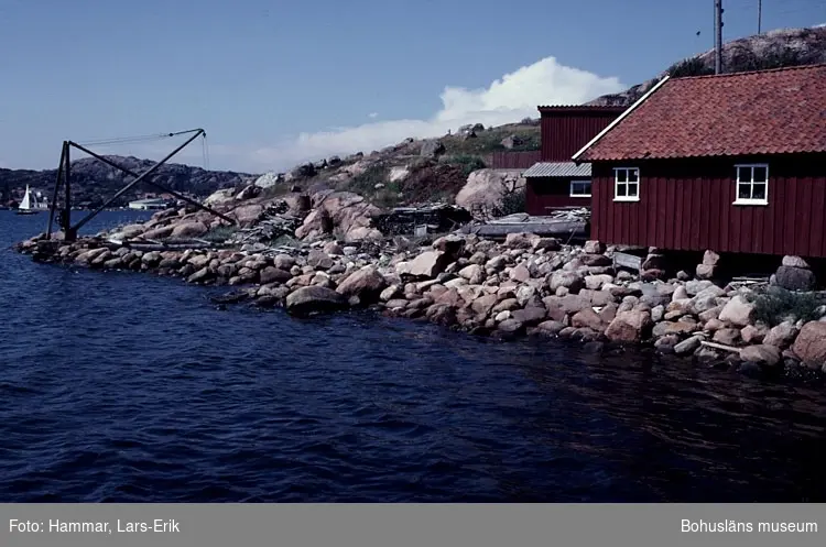 Motivbeskrivning: "F.d varv i Skredsvik, Bottnafjorden. Varvet drevs av båtbyggare Johan Jonasson fram till år 1942 och av Karl Johansson 1942-1975." "På bilden syns till vänster till vänster båtbyggarverkstad, till vänster virkesmagasin. Till vänster kran tillhörande varvet."
Datum: Juli 1980.