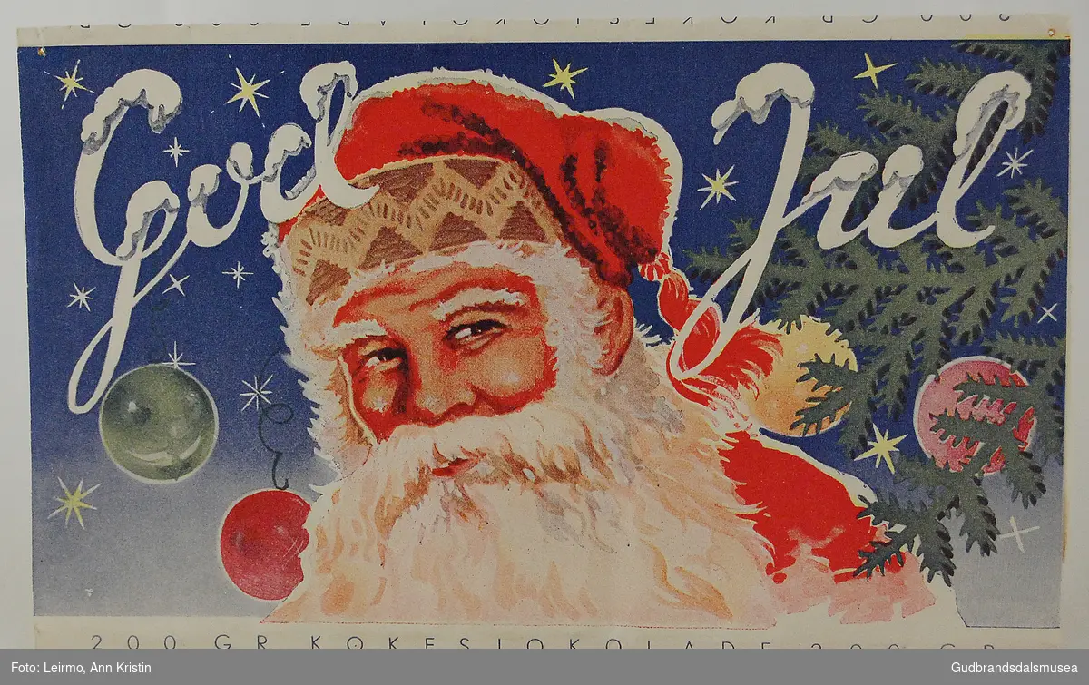 Papiremballasje, har vært rundt en kokesjokoladeplate. Dekorert med julemotiv, julenisse og påskriften God Jul. 
I følge giver fra julen 1939.