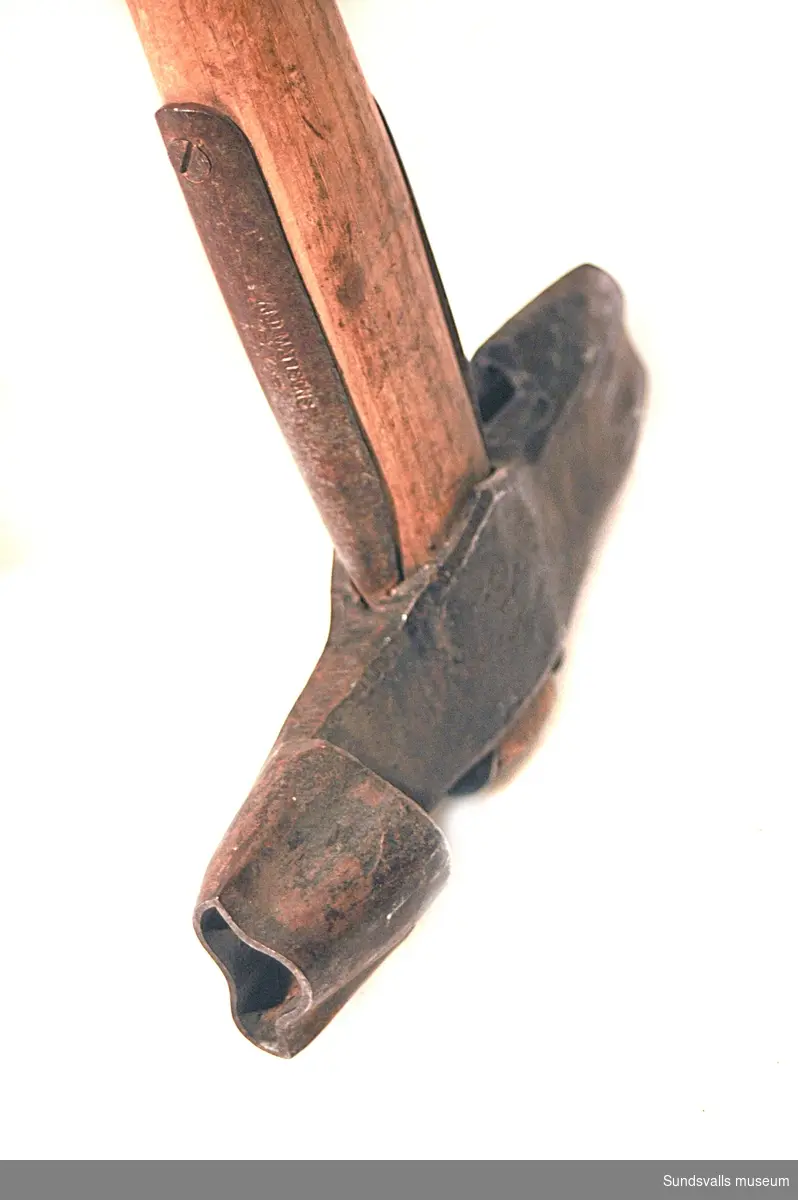 Märkyxa med träskaft. Huvudet mäter 19 cm och har oregelbundet formade huggmärken. Användes av Nyhamns AB.