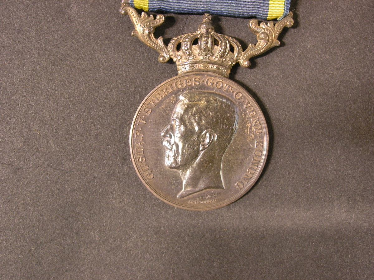 Medalj tilldelad förste postvaktmästaren C A Adamsson för
"Nit och redlighet i rikets tjänst". Medaljen är av silver med ett
blått och gult sidenband. Medaljen skall bäras på bröstet. Medaljen
visar på åtsidan kung Gustaf V i profil åt vänster. Frånsidan har en
lagerkrans över inskriptionen "TILL FÖRSTE POSTVAKTMÄSTAREN C A
ADAMSSON" i fyra rader. Medaljens ovansida har en kunglig krona och
två lagerkvistar som bildar en upphängningsanordning för sidenbandet.