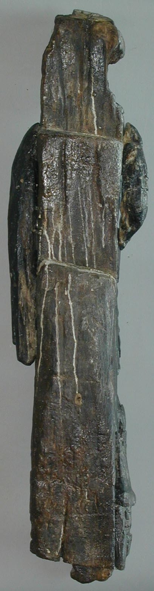 Kejsare. Skulptur föreställande en mansfigur med lagerkrönt huvud och slätrakat ansikte. Figuren är iförd romersk rustning - troligtvis av thoraxmodell - med mantel. Manteln är draperad i rika veck över bröst och mage och hopfäst på höger axel.
Figurens kropp är frontalt riktad, med huvudet vridet något mot vänster. Kroppen stöder på vänster ben medan höger ben hålls böjt och något fört åt sidan. Upptill är bakstycket framdraget i en "huvudplatta".



Figuren står på en sockel, vilken pryds av en maskaron. Maskaronen har stora, stirrande ögon, platt och bred näsa samt grinande mun. Under maskaronens mun är en namnbanderoll placerad. Dess vänstra del upptar ett A, föregånget av en bokstav som kan tolkas som ett C eller G. Efter A:et följer ett litet ornament, placerat rakt under maskaronens mun, varefter kommer bokstaven L. Resterande bosktäver är helt utplånade.



Skulpturens baksida är rak och uppvisar tre snedställda, olika djupt liggande fält. De tre fälten, som utgör anliggningsytor, ger skulpturen en trappstegsformad profil.

Skulpturen är relativt välbevarad, förutom figurens ansikte som är mycket slitet. Båda armarna är bortbrutna, en arm är funnen separat, men det är osäkert om det är höger eller vänster arm. Vidhängande delar av mantelns vänstra sida är fastskruvad. Stora partier av huvudplattan saknas. Maskaronen på sockeln är sprucken och ett parti på vänster sida saknas.



Text in English: Sculpture representing a male figure with laurel-wreathed head and a clean-shaven face. The figure is wearing thorax armour with the mantle richly folded over the chest and stomach and fastened at the right shoulder.



The figure''s head inclines slightly to the left while the body faces forward. The body rests on the left leg, while the right is slightly bent.

The upper part of the back extends upwards in a "head board".



The figure stands on a plinth decorated with a mask. The mask has large, staring eyes, flat broad nose and grimacing mouth. Beneath the mask there is a name inscribed: beginning with either CA or GA, after the A there appears to be a small ornament which is followed by the letter L. The remaining letters are indecipherable.



The sculpture''s back has three obliquely placed flat surfaces of different depths, that are areas of attachment. The flat surfaces make the sculpture look like a step-ladder in profile.

The sculpture is rather well preserved apart from the face which is very damaged. The figure''s arms are broken off. One arm was found separately, but it is not clear whether it is the left or right arm. Parts of the mantle and the board over itÂ´s head are missing.