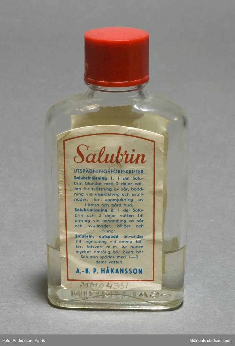 Salubrin, enkel glasflaska med röd skruvkork. Etiketten ser ungefär likadan ut som den första Salubrinflaskan som kom i handeln 1893. Innehåll kvar i flaskan. 