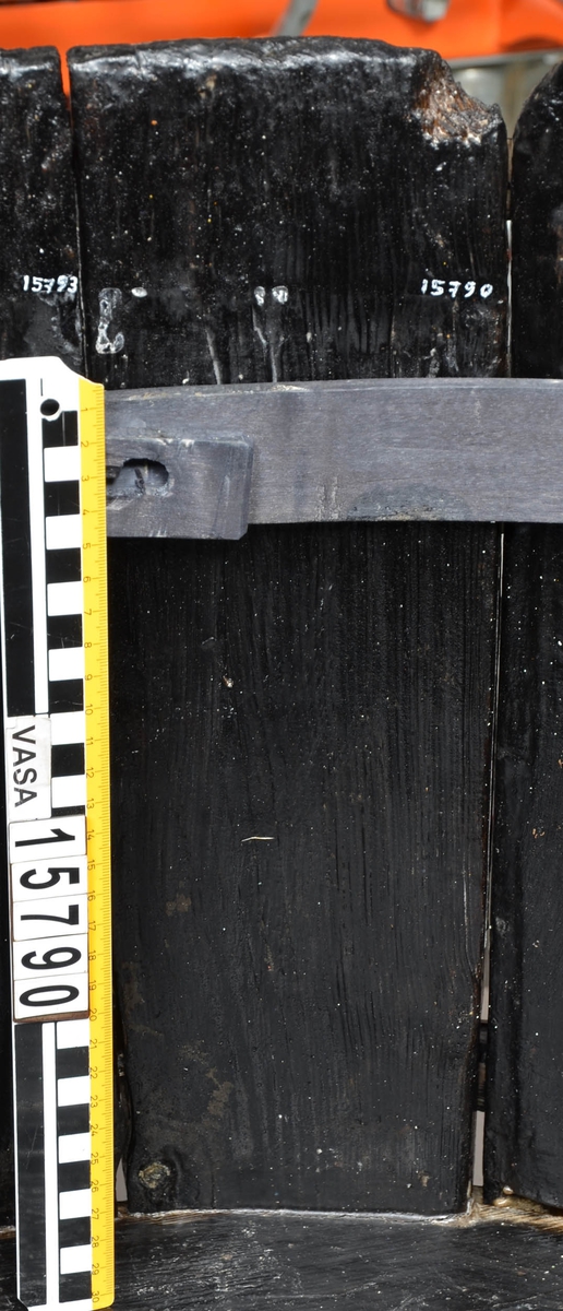 Laggstav till en balja. Två urtag på stavens nedre del. Den ena sitter på insidan, vid ena hörnet och är till för att staven ska passa in i intilliggande laggstav (15793). Det andra urtaget är ett hugget spår där baljans bottenplatta sitter.
Staven har ett skadat hörn.