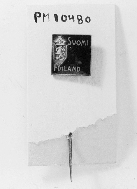 Rockslagsnål, fyrkantig med svart emaljplatta med finska riksvapnet i rött och texten: Suomi Finland i vitt.