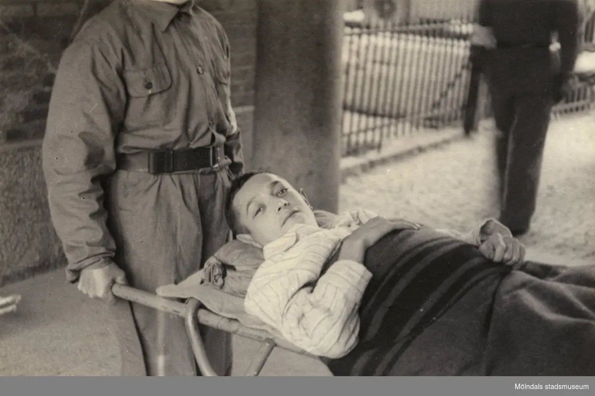 "Karantänsförläggning" på Kvarnbyskolan för överlevande från koncentrationsläger i Tyskland och Polen 1945.  
Skolan fungerade under denna sommar som beredsskapssjukhus.

På båren ligger Abraham Frischer, 22 år gammal, överlevande från koncentrationsläger i Tyskland.