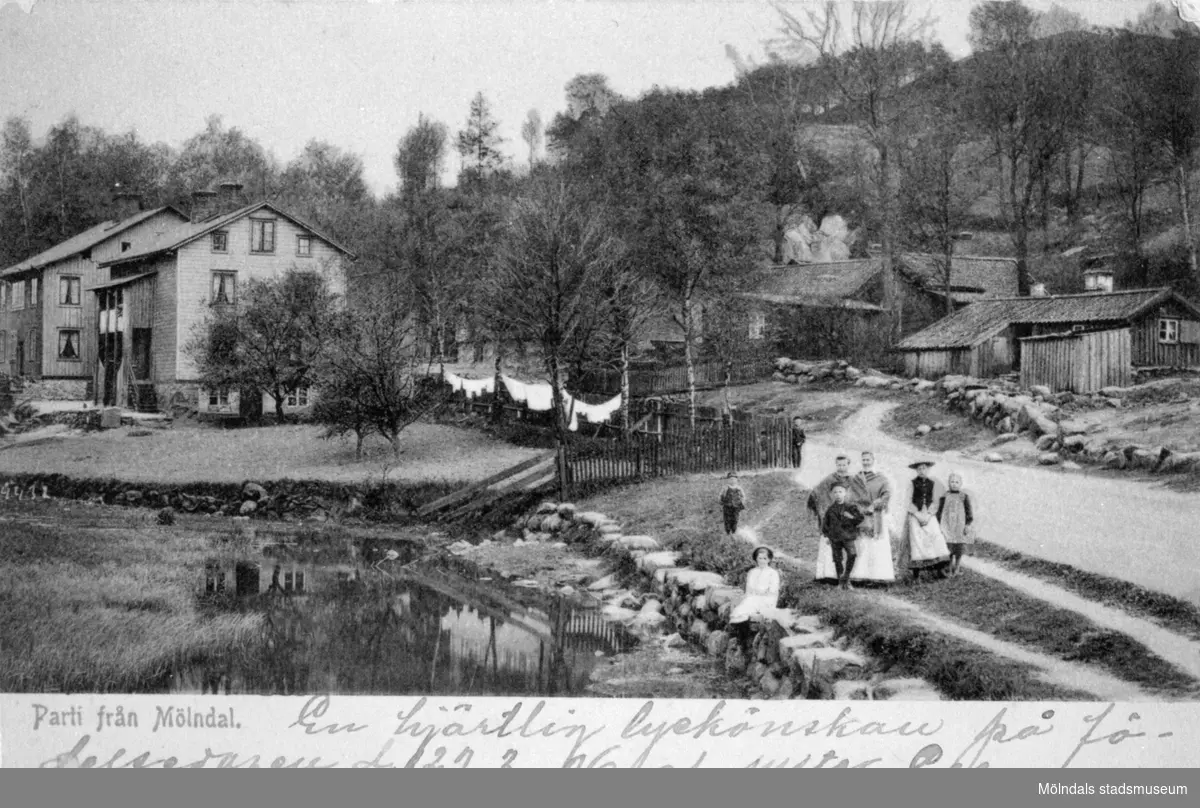 Vykort "Parti från Mölndal" postat den 28/3 1906. Man ser en del av Pixbovägen strax öster om Grevedämmets skola. Man ser Roten I 17, 18, 4 och 2 (Pixbovägen 17, 18, 4 och 2). Fotot är taget en söndag då det var lågvatten.