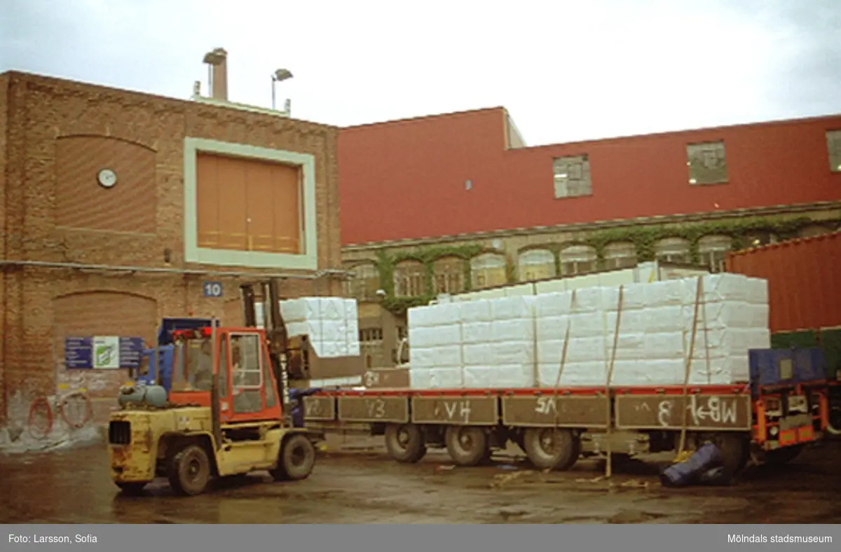 En truck kör framför byggnad 10 (pappersmaskinhall). I bakgrunden ses byggnad 18 (kromofabrik). Papyrusinventering 2001-10-23.