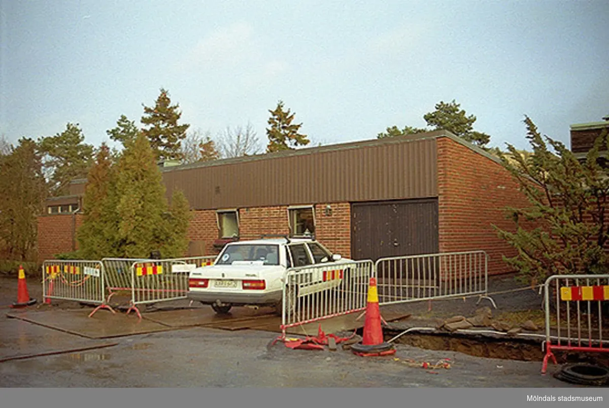 Byggnadsdokumentation. Vy från väster på fastigheterna Ribbstolen och Torpet i Mölndal. Villa med garageinfart och parkerade bilar utanför samt pågående vägrenovering. Oktober 1998 - januari 1999.