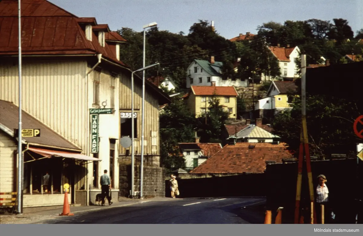 C.J. Johanssons Järnhandel på (Järnhandelsliden) Kvarnbygatan 27 och Gamla rådstugan på nr 29  i Mölndal, 1970-tal. Till höger ses Papyrusmuren och i fonden ses Mölndals Kvarnby.