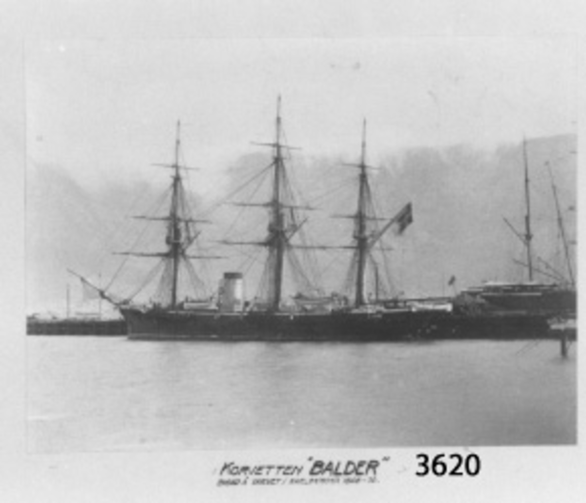 Fotografi, i glas och ram, av korvetten "Balder" förtöjd vi kaj. Fartyget byggt på varvet i Karlskrona åren 1868-70. Upphandlad år 1929 av Artilleridepartementet.