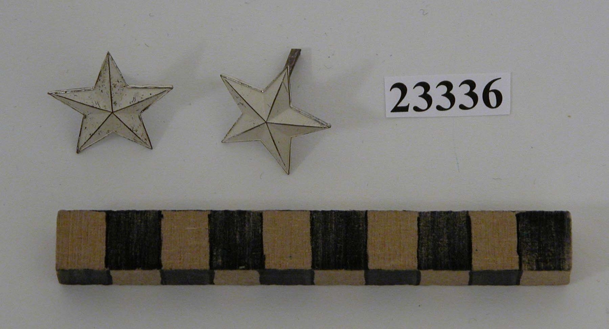 Yrkesbeteckning (ett par) i silver genom (vitmålad) stjärna för axelklaff och armbindel för marinintendentslinjen, reservlinjen, vid marinens kadettkår.