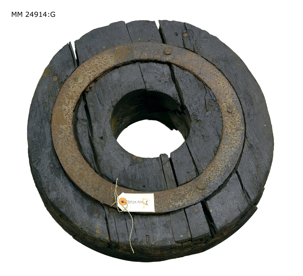 Svart hjul som består av flera hopsatta delar som hålls samman av en järnring. Hål i mitten för hjulaxeln.