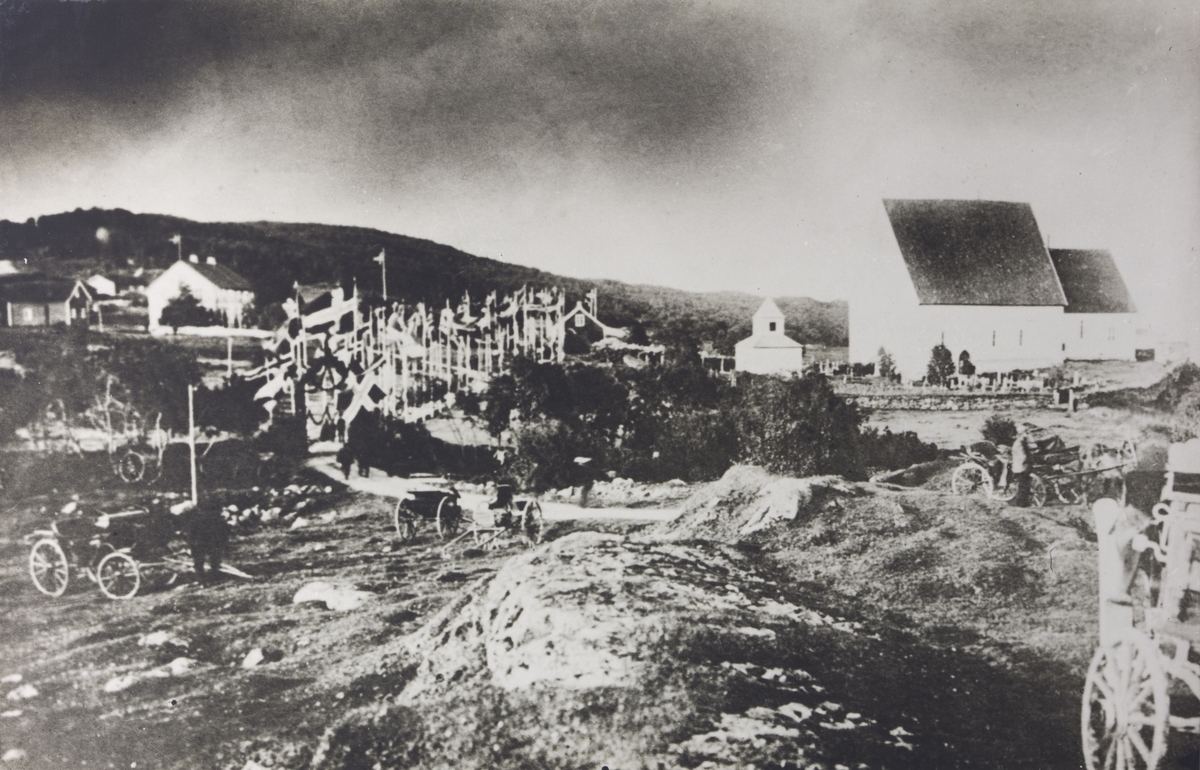 Hester, vogner og flagg ved Trondenes kirke og prestegård. Bildet er tatt i forbindelse med kongebesøket på Trondenes i 1907.