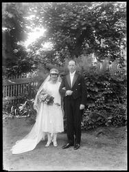 Brudepar fotografert fotografert i hage. Hvit kjole og smoki