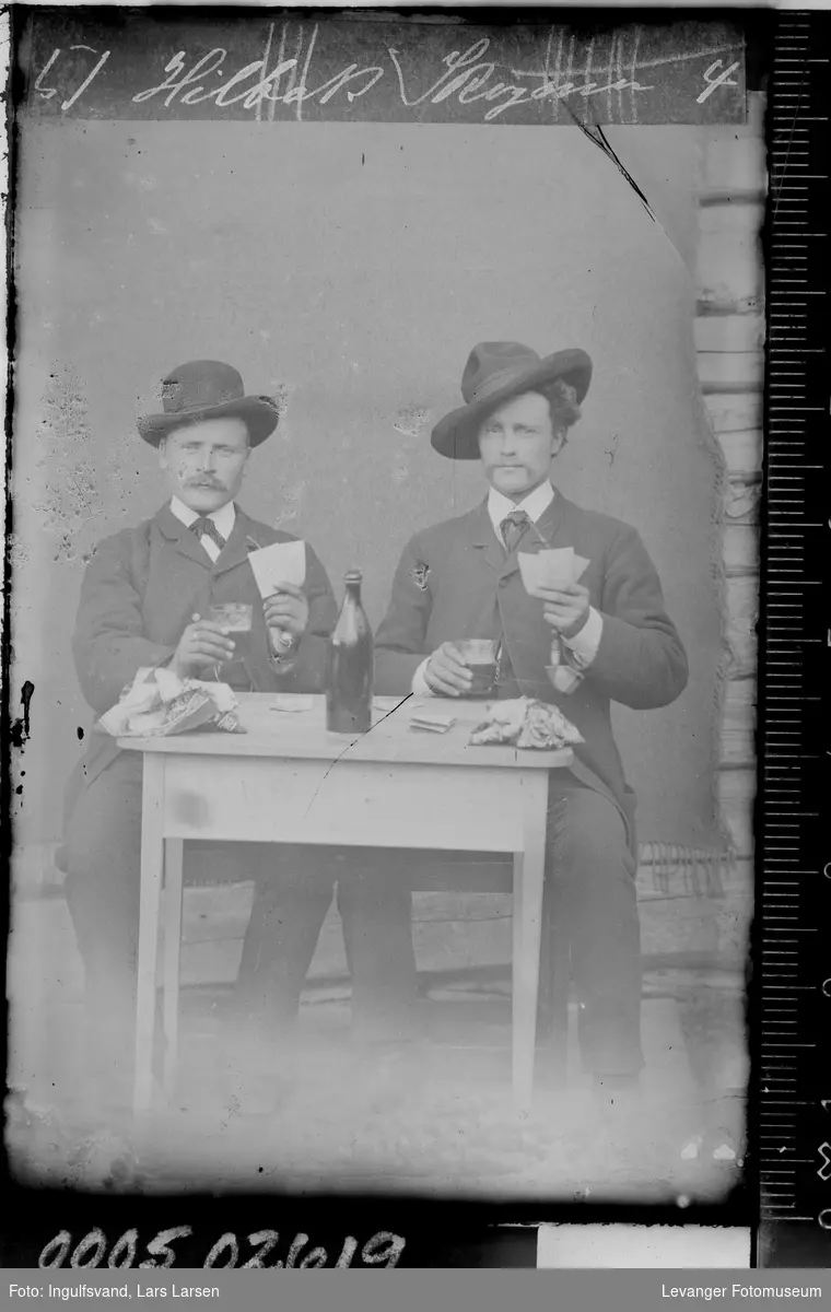 Portrett av to menn ved et bord som spiller kort.