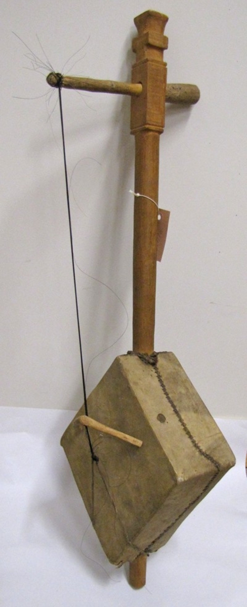 Stränginstrument med en sträng av tvinnat tagel. Instrumentet har ett gitarrliknande utseende med en

resonanslåda av skinn med måtten: L . 29 cm .   H . 12,5 cm. B. 23,5 cm, samt en arm av trä. Strängen är fästad längst bak vid resonanslådan och hålls uppe av ett stall . Instrumentets hela längd är 80 cm . Instrumentet spelas med en stråke av trä och tagel.

21 412:a  Instrumentet
       ''    :b  Stråken

Ägaren var musiklärare vid gymnasieskolan i Vänersborg där instrumentet förvarades . Ägaren var en mycket välkänd profil inom musiklivet i Vänersborg.

Givaren var änka efter ägaren.