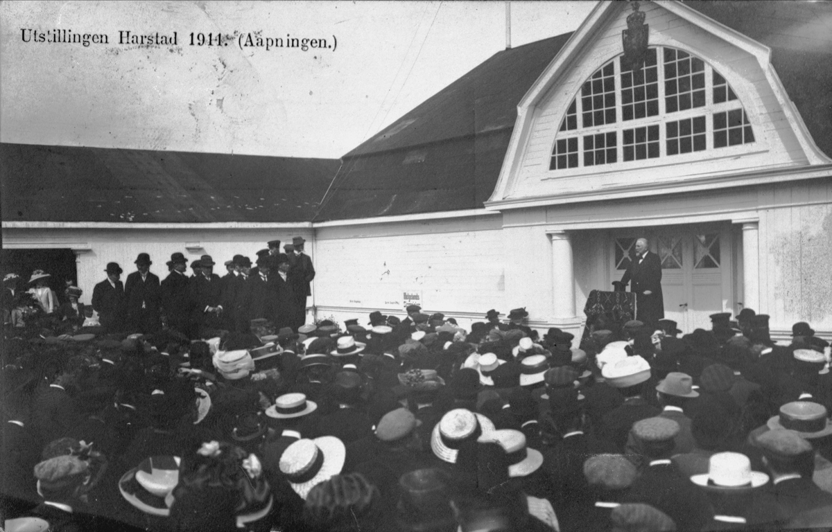 Folkemengde og mann på talerstol foran paviljongen på Hamnneset, fotografert under åpningen av Harstadutstillingen i 1911.