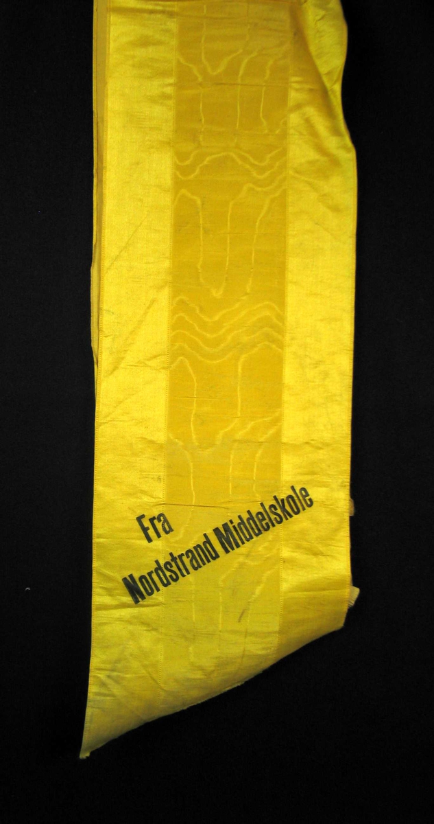 Begravelsessløyfe i gul silke med svart tekst.