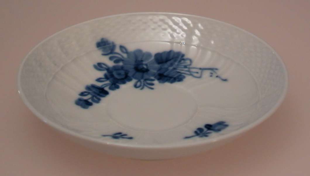 Kaffeskål i porselen med blå blomsterdekor.
Riflemønster i godset..